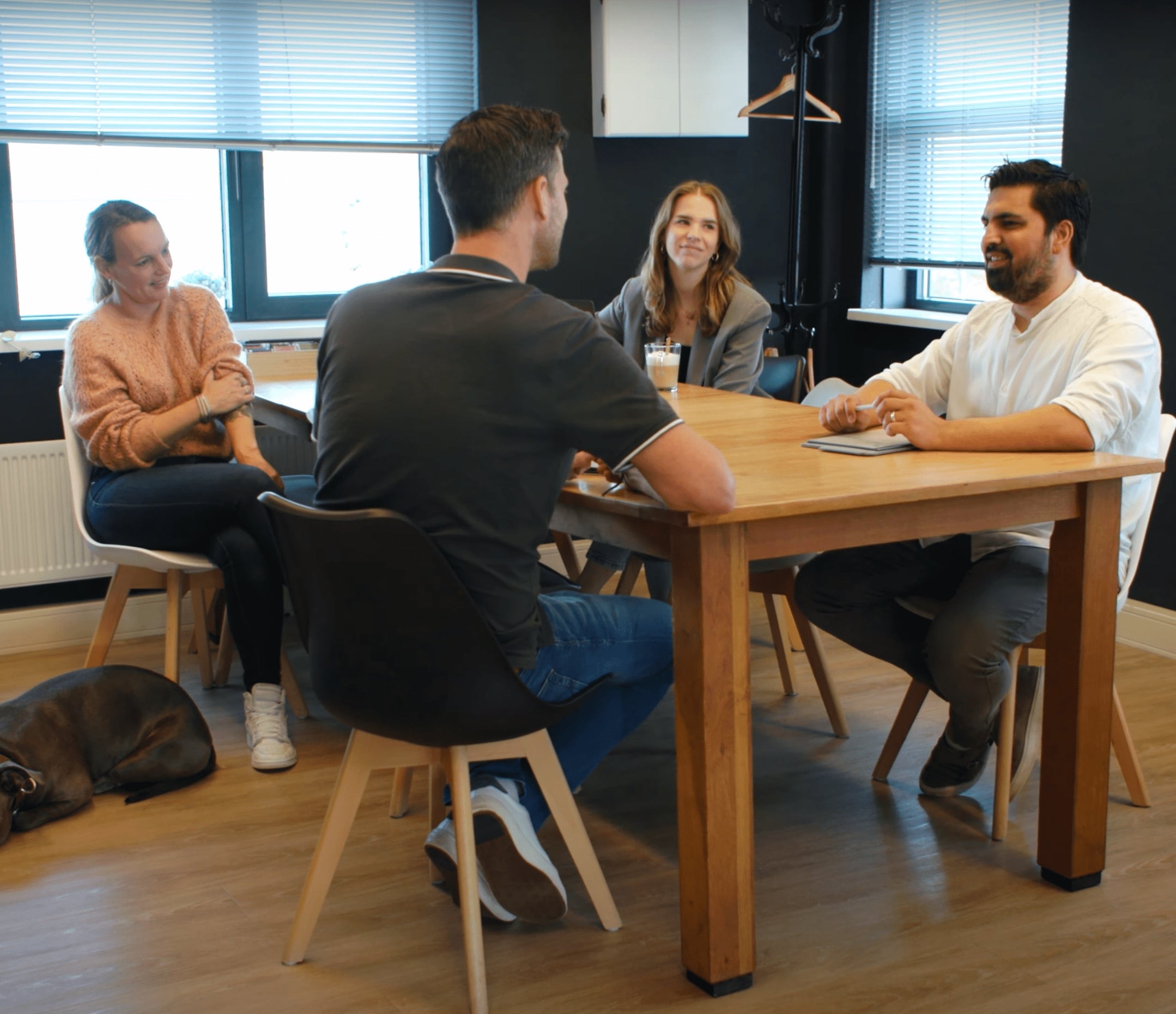 Het team van Tilstra Services in overleg, met Bella de kantoorhond op de vloer